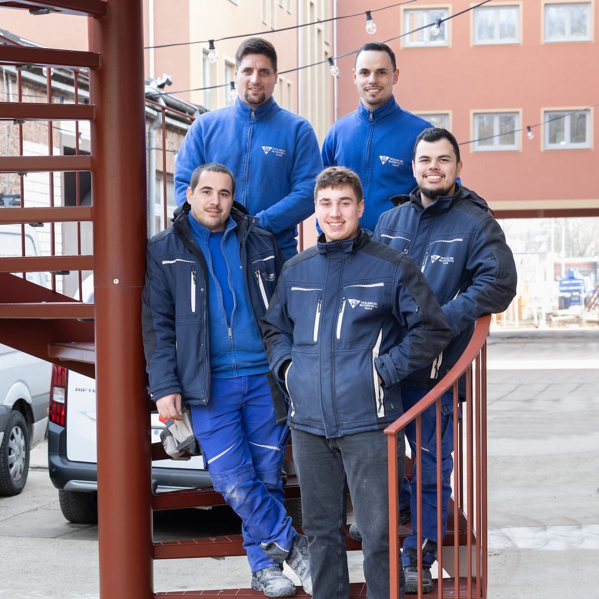 Fünf Fachkräfte stehe auf einer Treppe